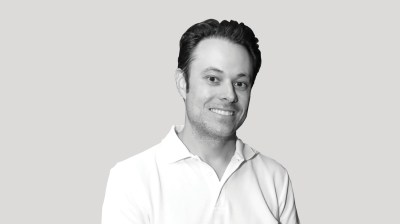 A silhouetted black-and-white portrait of white man on a gray background.