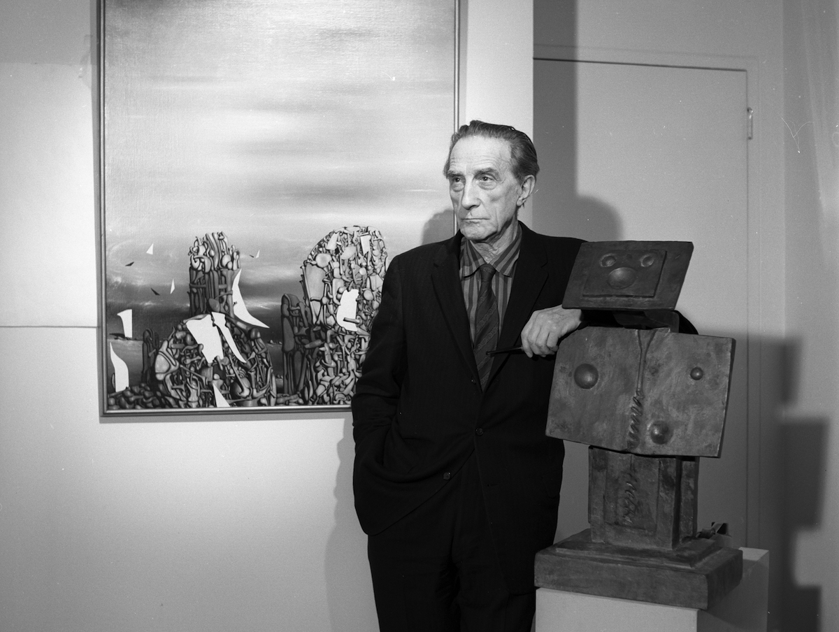 A man with an arm leaned against a sculpture of a man.