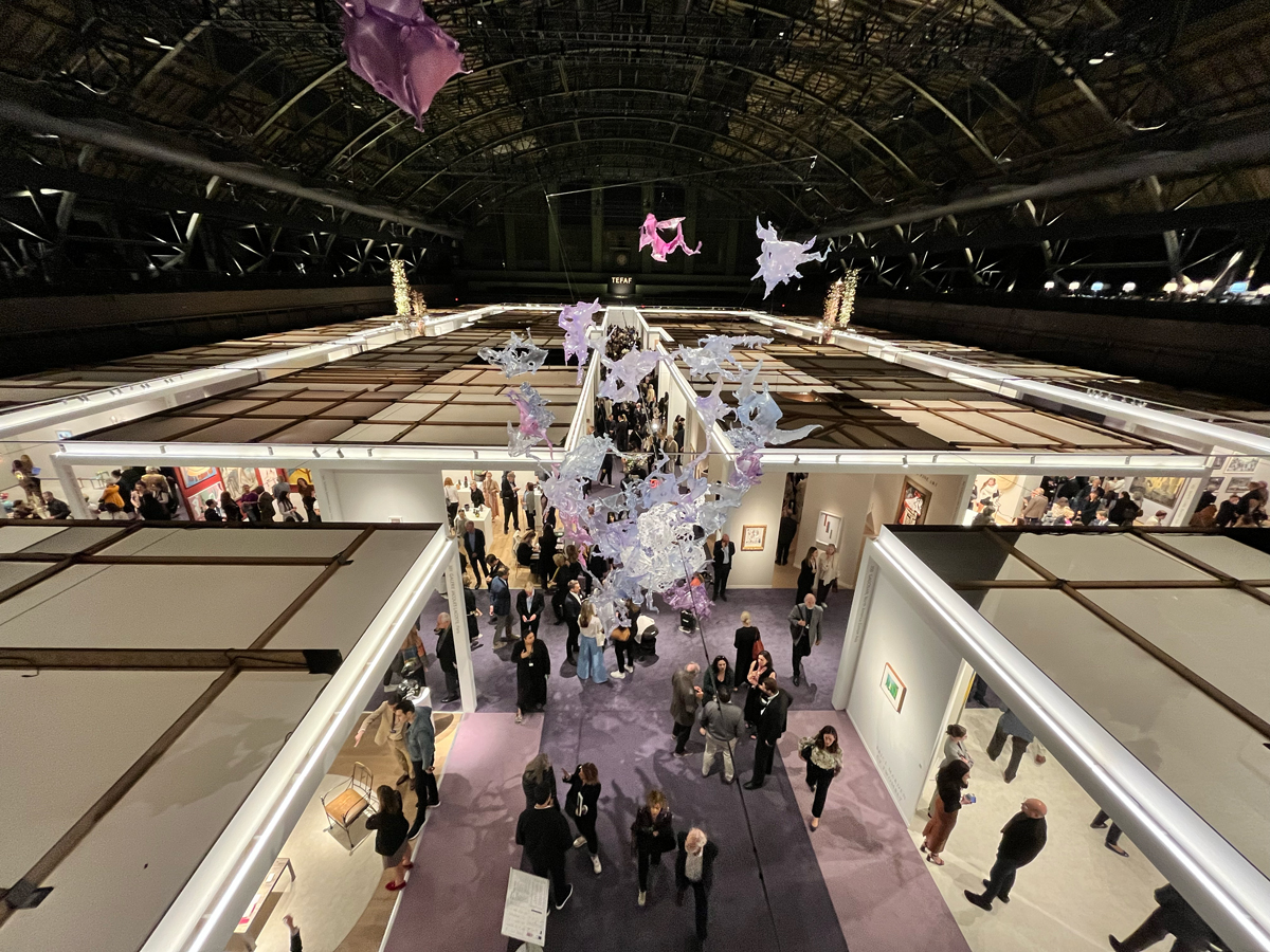 View of a vaulted drill hall with an art fair below.