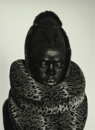 An image of a dark skinned black woman with an elaborate neck decoration that appears velvet.