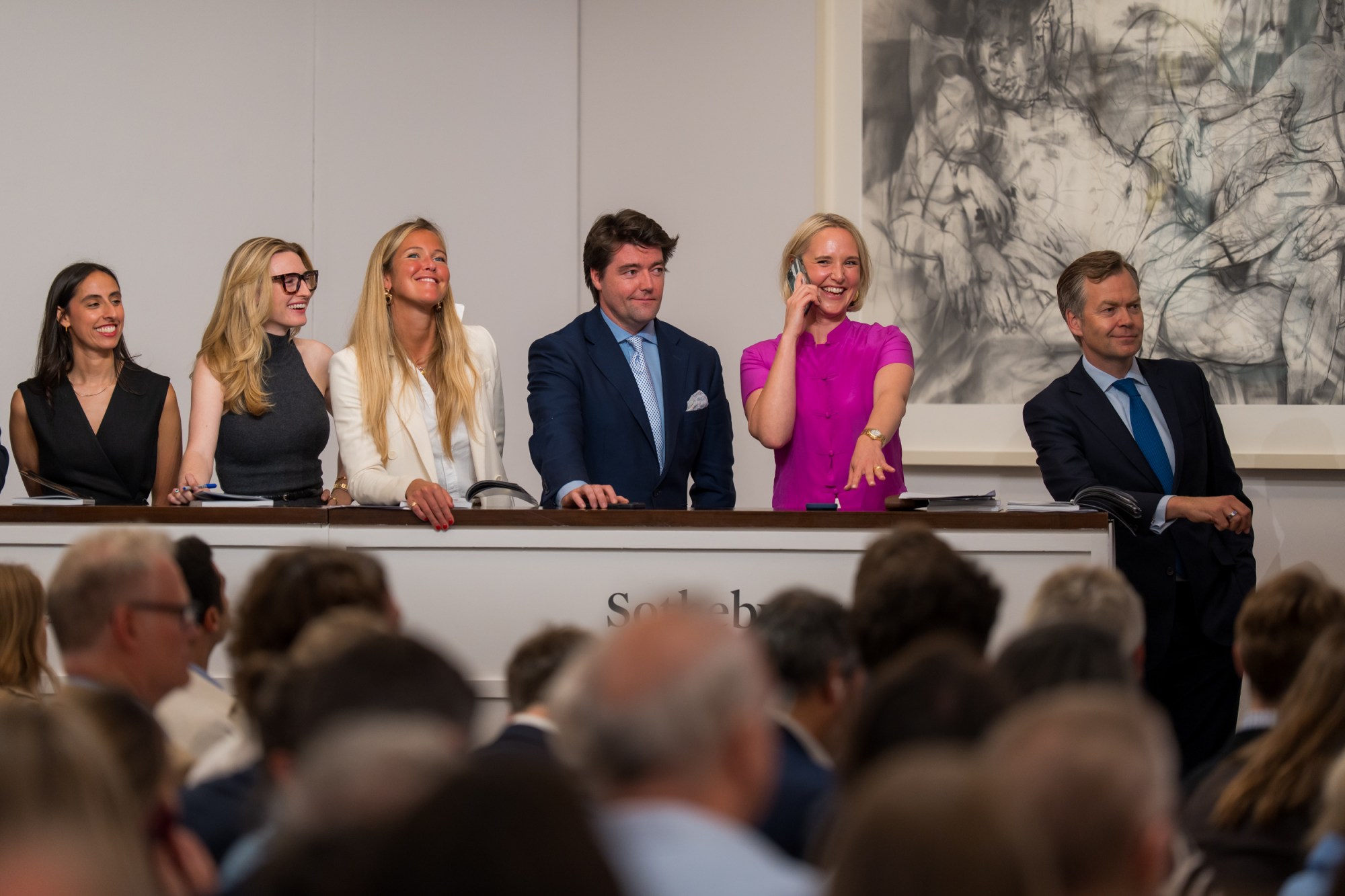 four smiling women and two smiling men in a row.
