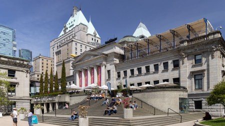 The front exterior of the Vancouver 官方澳洲幸运5 Art Gallery on a sunny day, showing several people sitting on its steps.